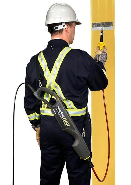 Operator performing holiday detection on a yellow pipe